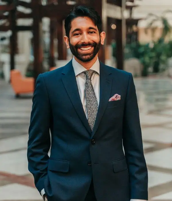 Dr. Harshal Kubavat standing in a blue suit with red pocket square.